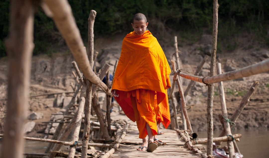 An apprentice monk crossing the bridge to Luang Prabang