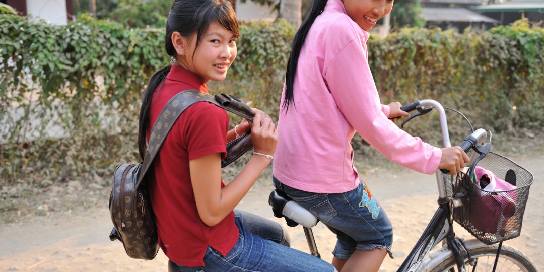 Por and Leh riding a bicycle near their home.