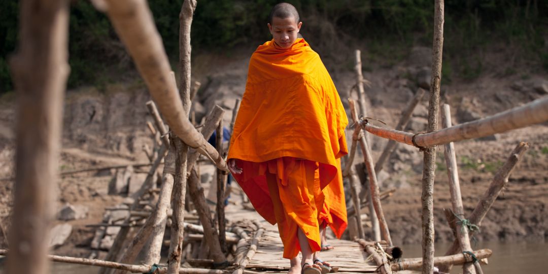 An apprentice monk crossing the bridge to Luang Prabang